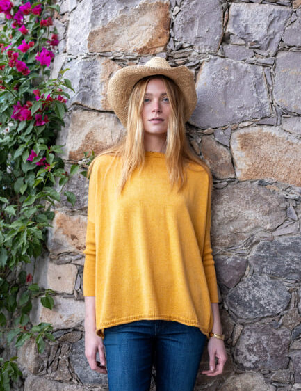 Image of a woman wearing a mustard yellow oversized crewneck sweater with side slits