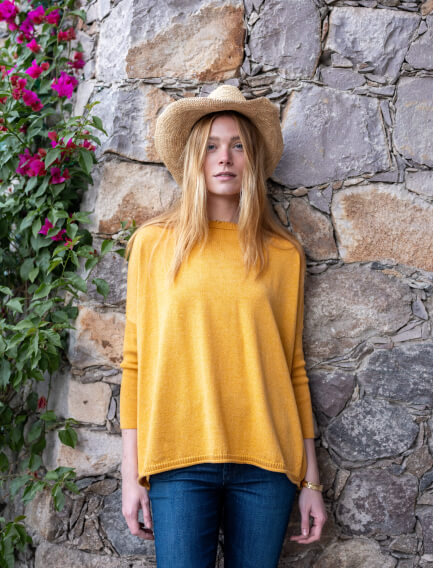 Image of a woman wearing a mustard yellow oversized crewneck sweater with side slits