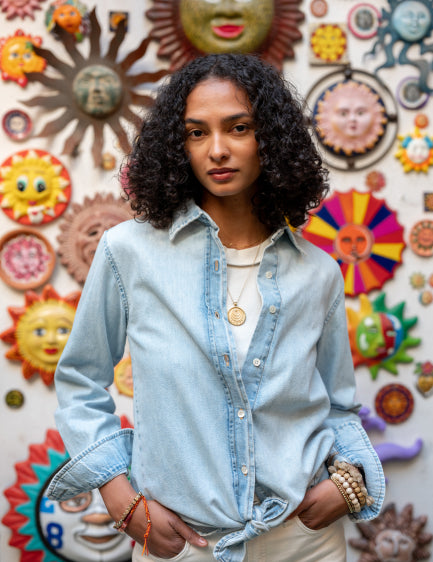 Image of a woman wearing a light blue denim long sleeve button up shirt