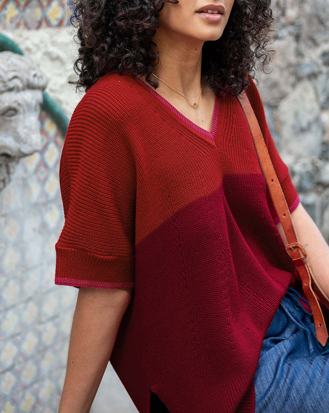 Close up image of a woman wearing a red and burgundy v-neck short sleeve sweater