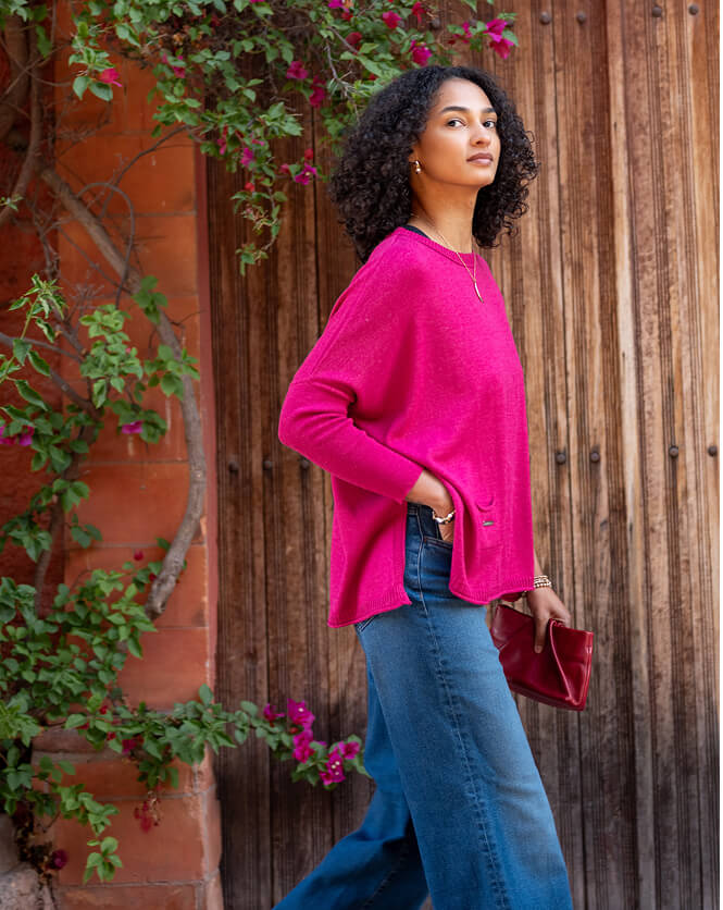 Image of a woman wearing a pink oversized long sleeve crewneck sweater with side slits
