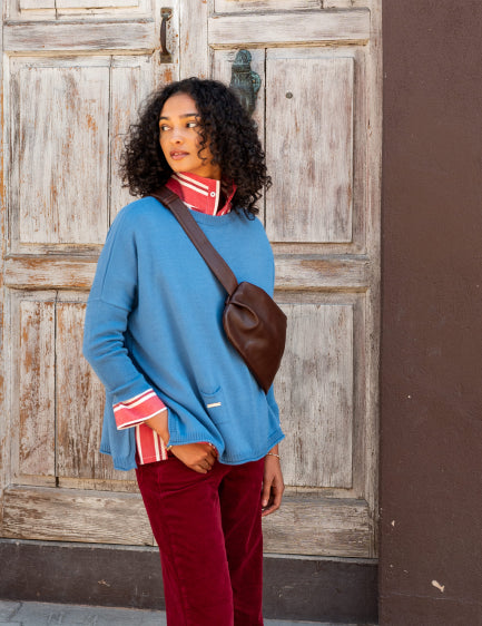 Image of a woman wearing a blue oversized crewneck sweater with side slits