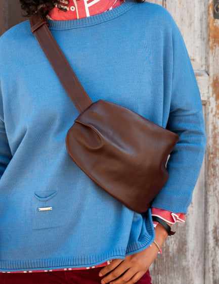 Close up image of a woman wearing a brown leather over the shoulder bag