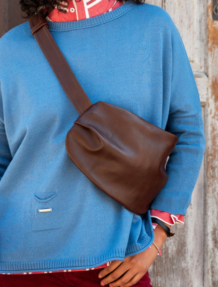 Close up image of a woman wearing a brown leather over the shoulder bag