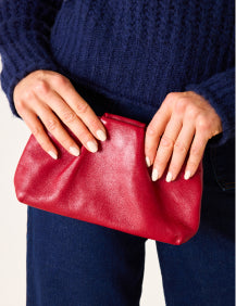 Close up image of a woman holding a red leather clutch