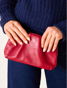 Close up image of a woman holding a red leather clutch