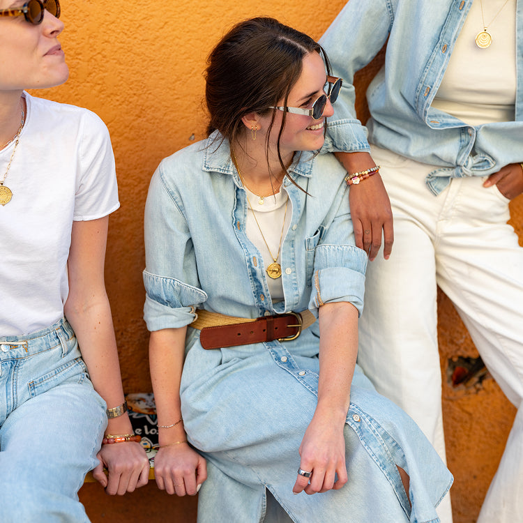 Close up image of three women wearing different light blue denim shirts, dresses and pants