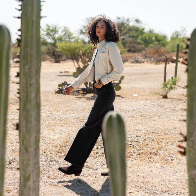 Woman walking through a desert landscape with cacti