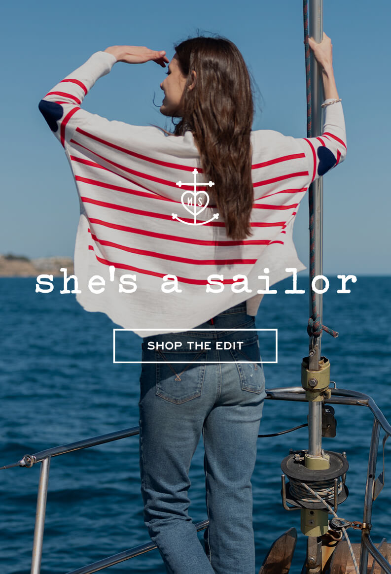 MERSEA women's travel-friendly cream knit top with red stripes and a nautical anchor logo. Text: she's a sailor SHOP THE EDIT