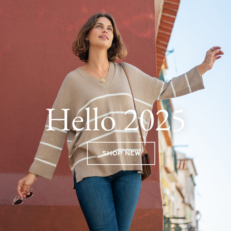 Hello 2025 - Shop New - a women wearing a cream and beige striped v neck sweater walking the streets of lisbon