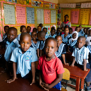 Kids standing in a classroom wearing blue and and red tee shirts