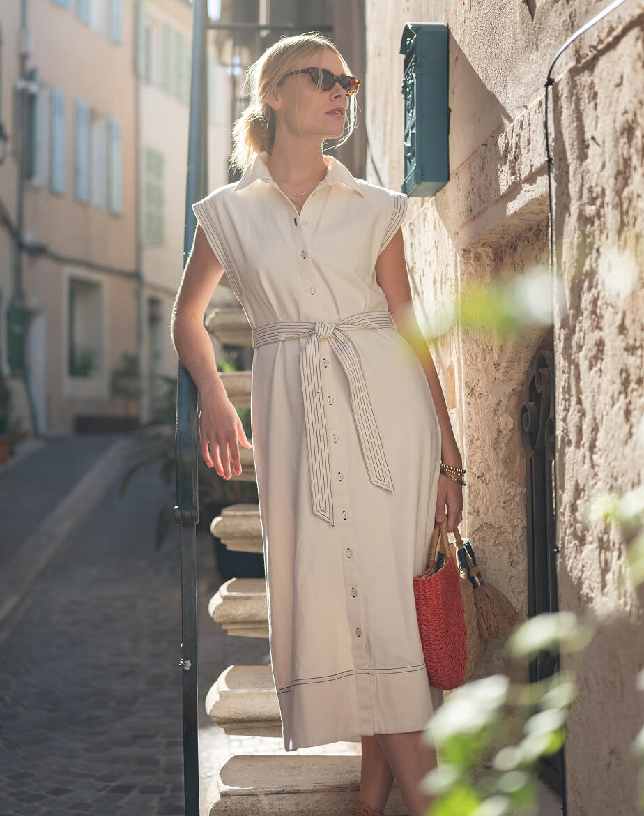 Woman in a white dress standing on stone steps in an urban setting