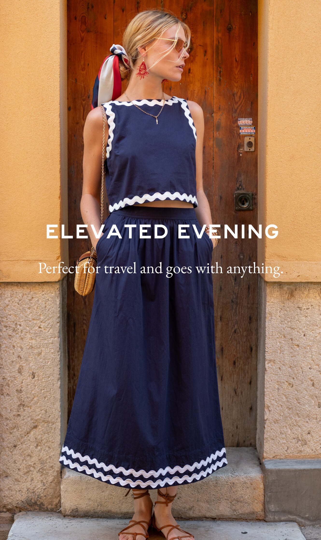 Woman wearing a navy dress with white trim standing in front of a wooden door.