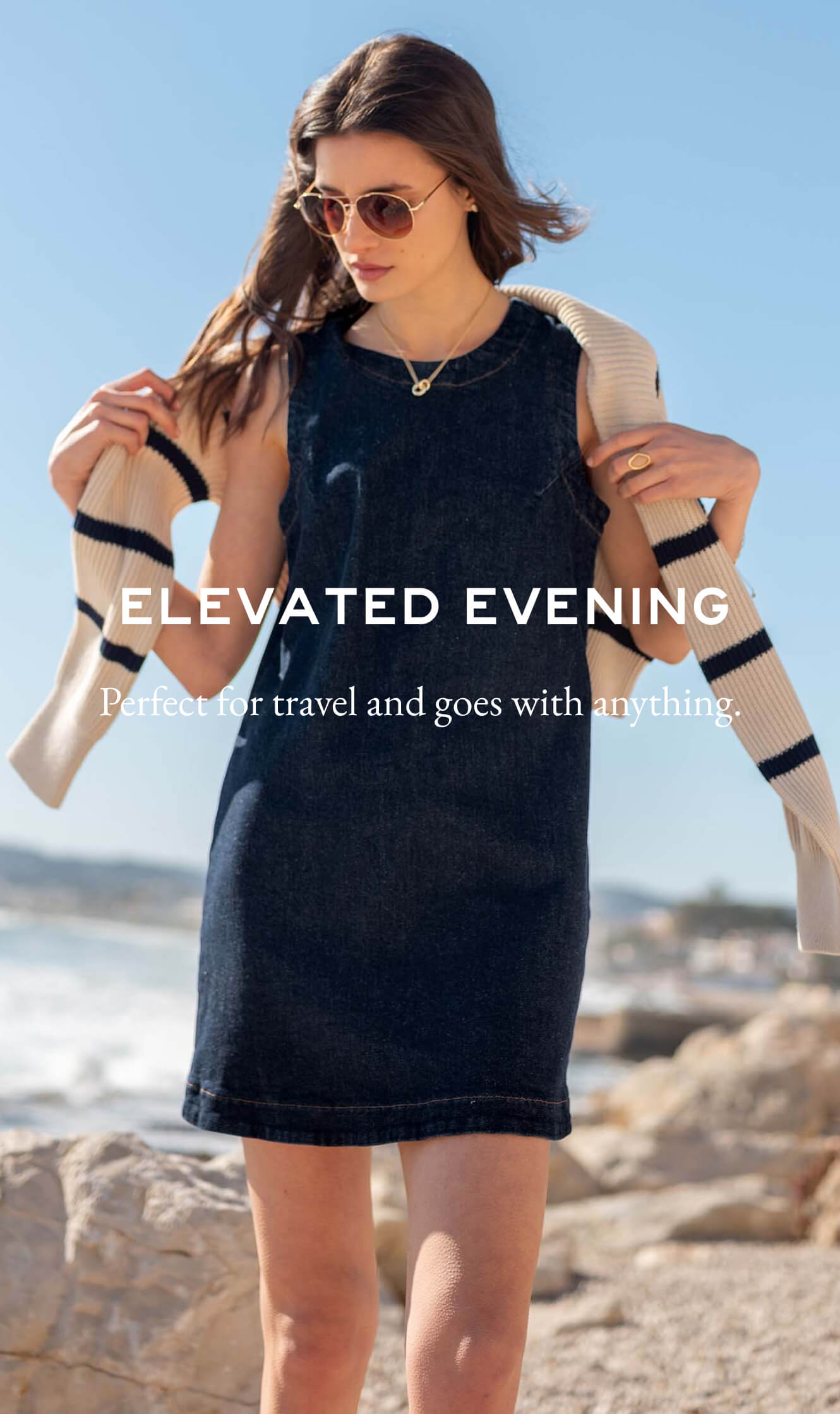 A woman on a beach wearing a navy blue sleeveless dress and an ivory knit cardigan with black stripes over her shoulders. Text: 'ELEVATED EVENING' 

Perfect for travel and goes with anything.