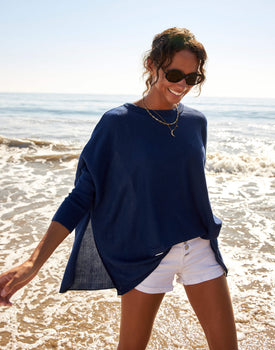 female wearing navy sweater with slit sides walking on the beach