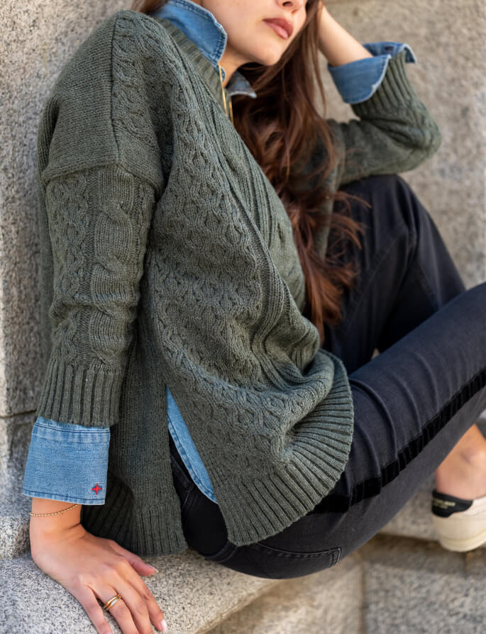 Olive green cable knit oversized sweater with denim-lined cuffs.