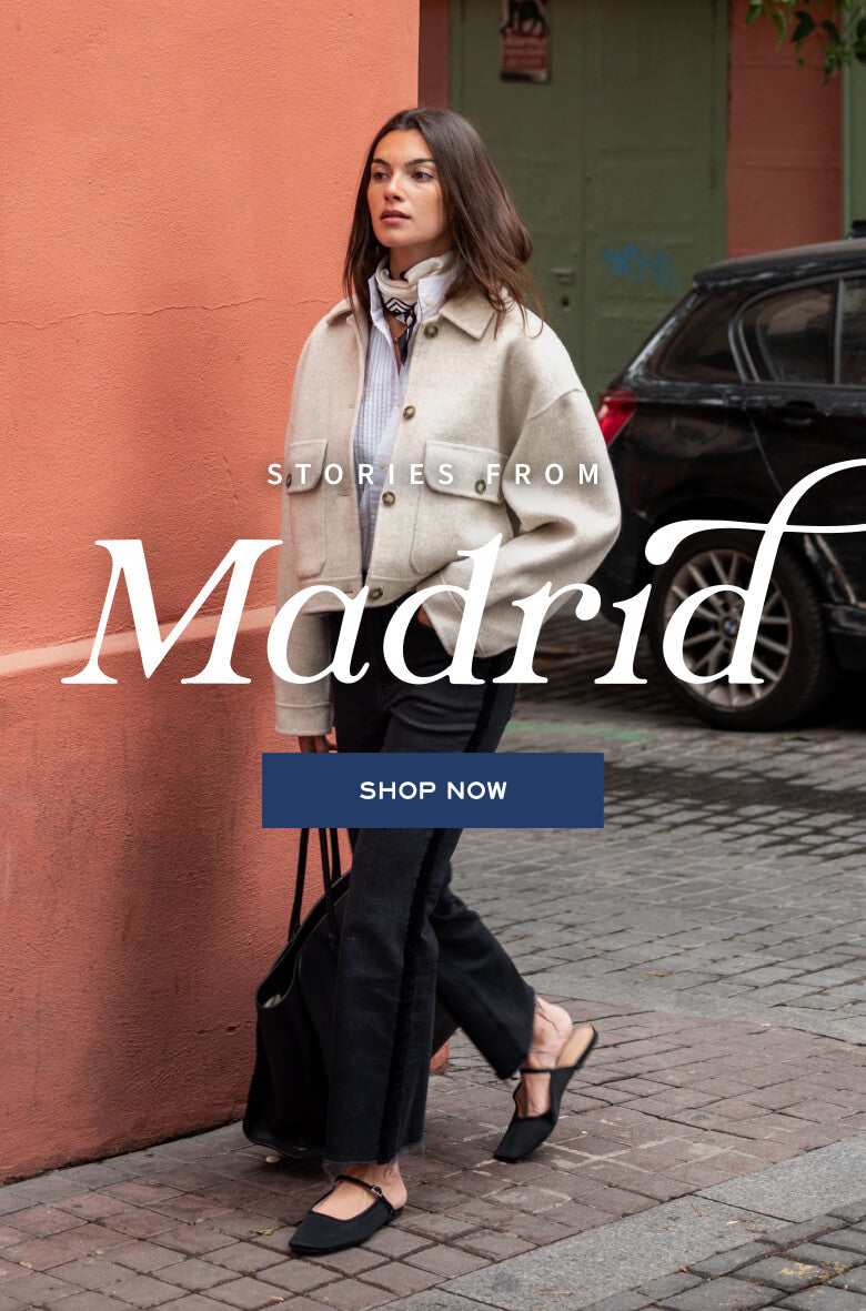 A woman in a stylish travel outfit posing in front of a peach-colored wall. Text: 'STORIES FROM Madrid', 'SHOP NOW'