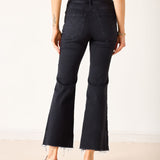 Person wearing black flared jeans on a plain background