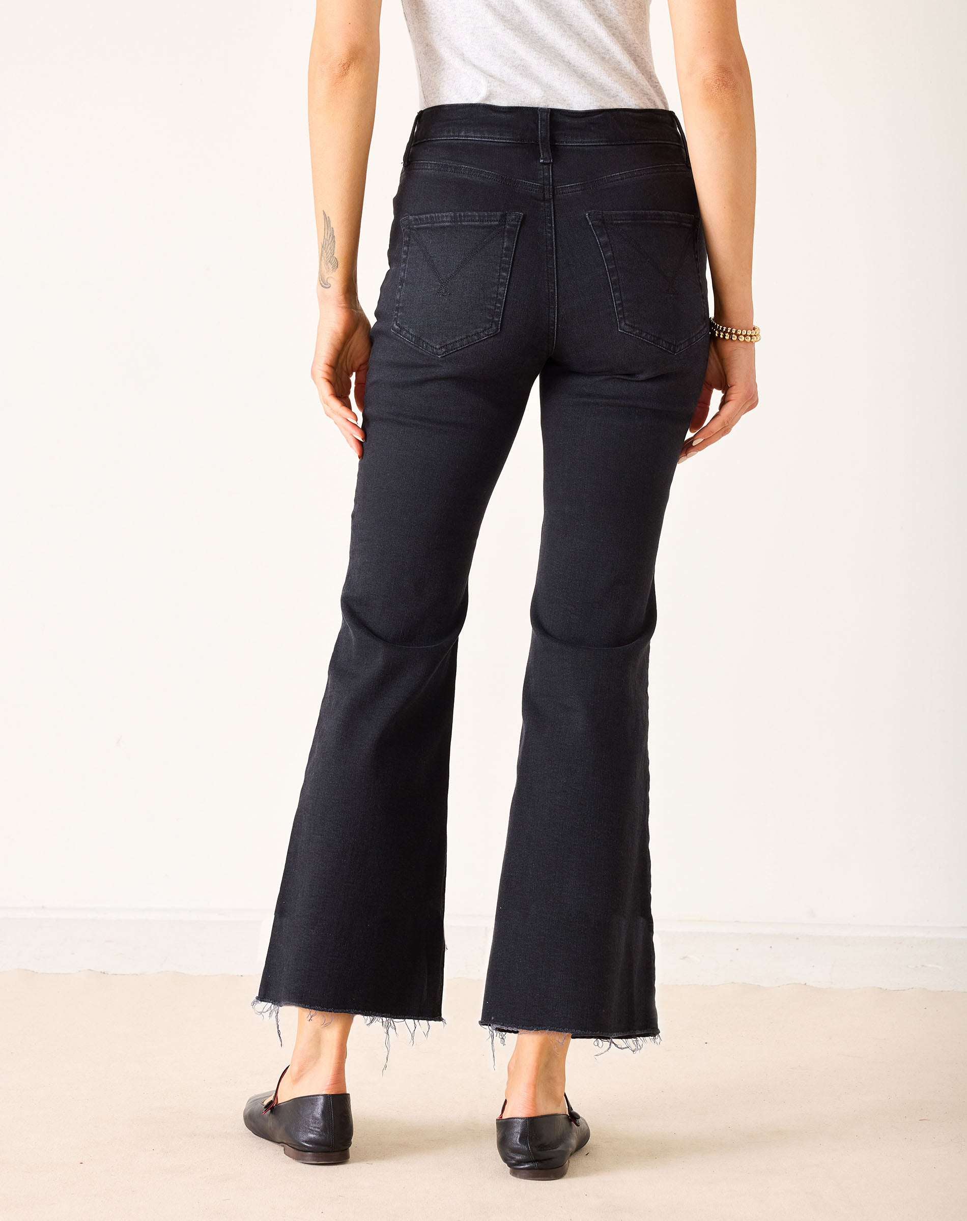 Person wearing black flared jeans on a plain background