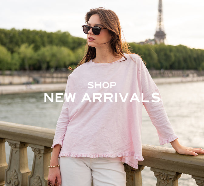Woman in a pink top and sunglasses leaning on a railing with text 'Shop New Arrivals' and the Eiffel Tower in the background.