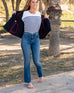 Woman showcasing Mersea Infinity blue Nomad cropped mini boot-cut jeans walking in park