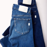 folded Mersea moody blue and Infinity blue Nomad cropped mini boot-cut jeans laying against white background