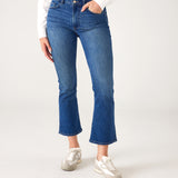 lower body of Woman wearing Mersea Infinity blue Nomad cropped mini boot-cut jeans standing against white background