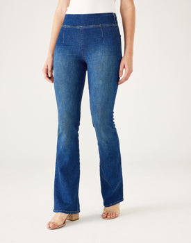 Lower body of Woman showcasing Mersea Nomad cadet blue denim full length boot-cut jeans against white background