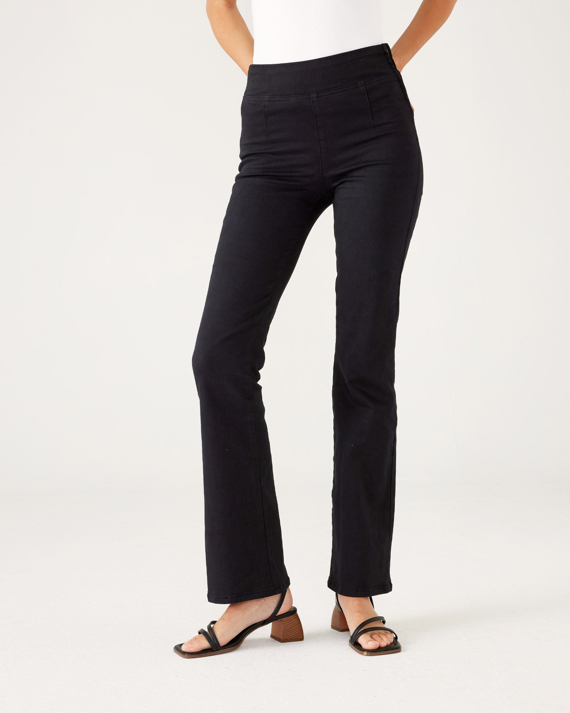 Lower body of Woman showcasing Mersea Nomad black denim full length boot-cut jeans against a white background