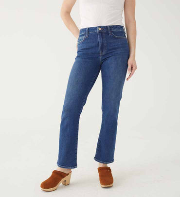 female wearing medium wash boot cut jeans with clogs on a white background