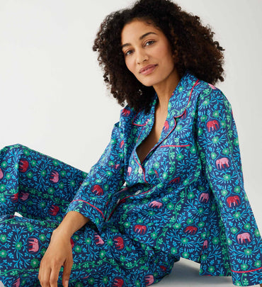 female wearing matching pajama set with elephant vine print sitting on a white background