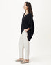 female wearing black v neck poncho with white pants and sandals on a white background