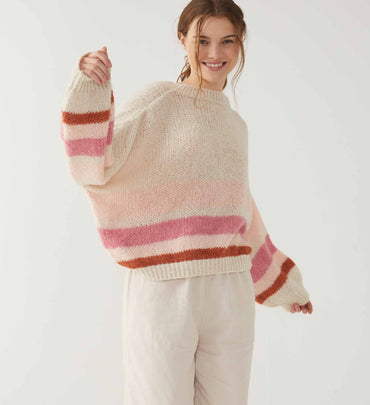 female wearing neutral and pink stripe sweater over neutral twill pants on a white background