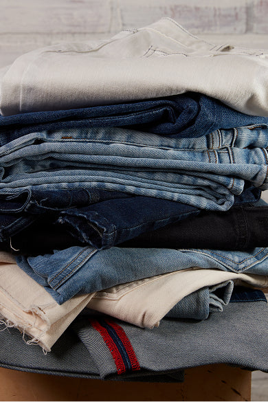 MERSEA women's travel-friendly ivory and denim blue pile of folded garments, including a linen shirt with embroidered detailing.