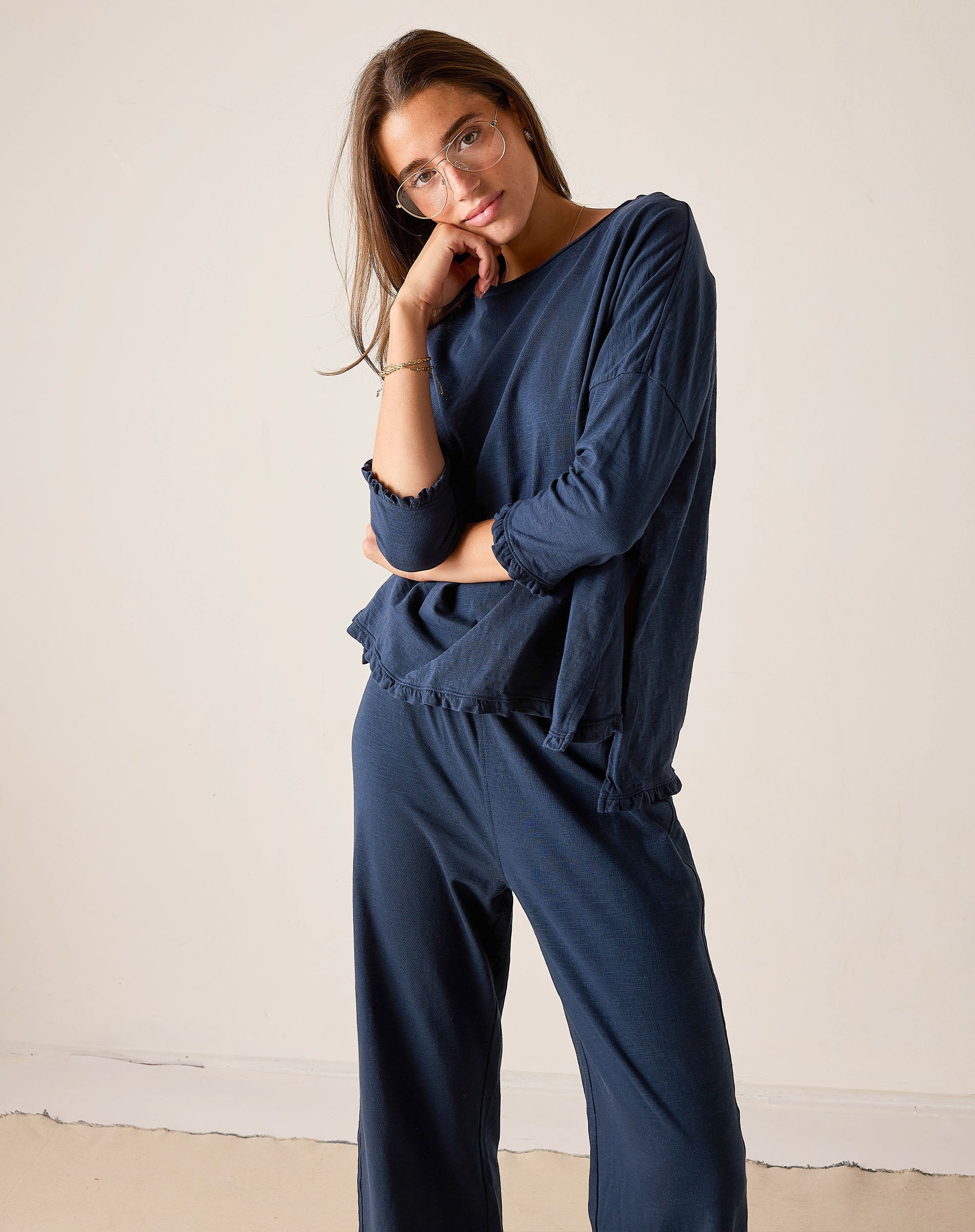 Woman wearing a navy blue outfit with a matching top and pants against a plain background
