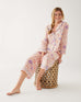 woman wearing mersea matching pajama set with peacock vines print sitting on stool