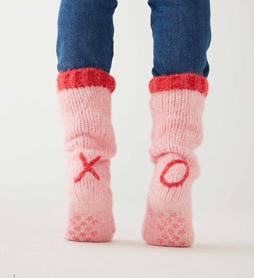 female wearing pink slipper socks with red lining and XO on ankles on a white background