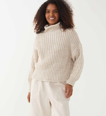 female wearing neutral knit turtleneck over neutral twill pants on a white background