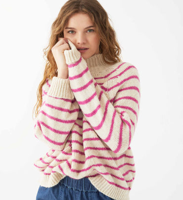 female wearing pink and neutral striped wide neck turtleneck sweater on a white background