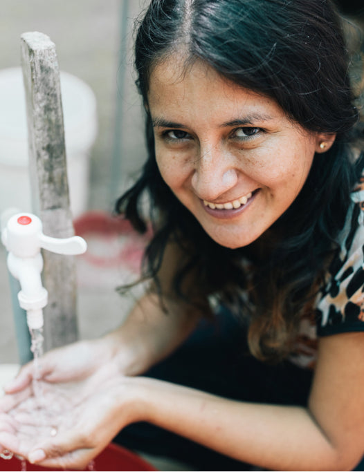 Dark hair woman holding water in her hands looks at the camera