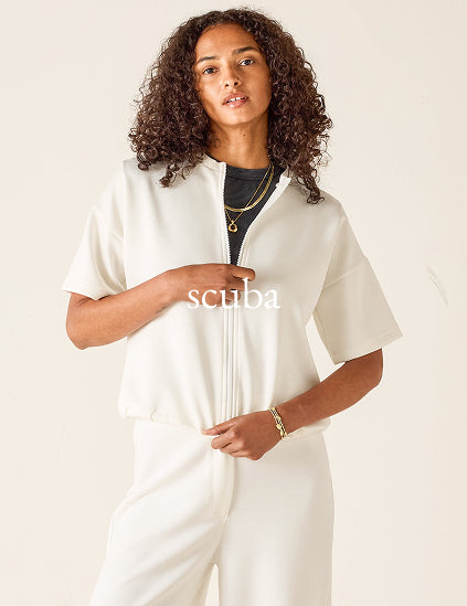 Woman wearing a white outfit with 'Scuba' branding on a beige background