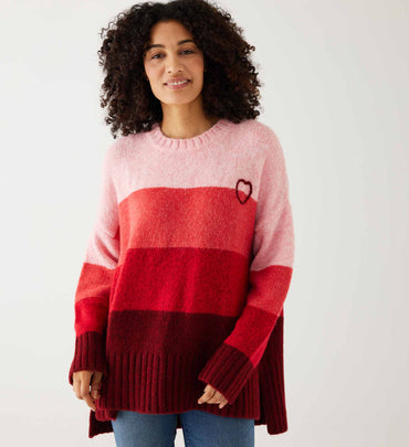 female wearing red striped sweater with heart over jeans on a white background
