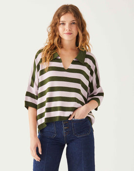 Female wearing a green and pink v neck sweater in front of white wall