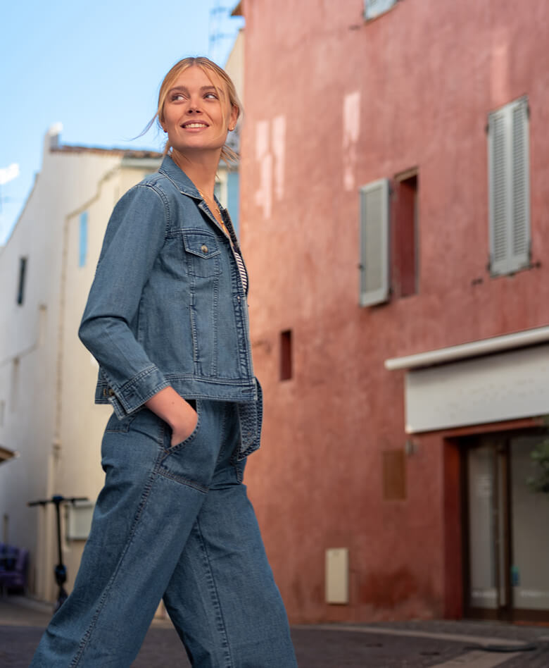 Image of a a woman wearing a denim jacket with matching denim pants.