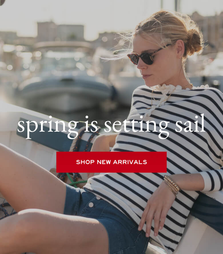 Woman sitting by a marina with text overlay 'spring is setting sail' and 'Shop New Arrivals'.