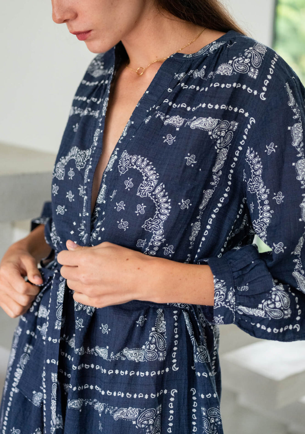 Woman wearing a navy blue dress with white pattern, standing indoors.