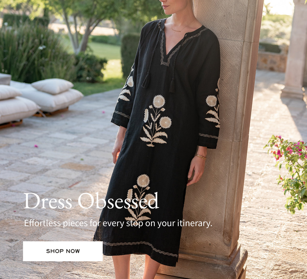 Woman wearing a black dress with floral embroidery in an outdoor setting, with 'Dress Obsessed' branding.