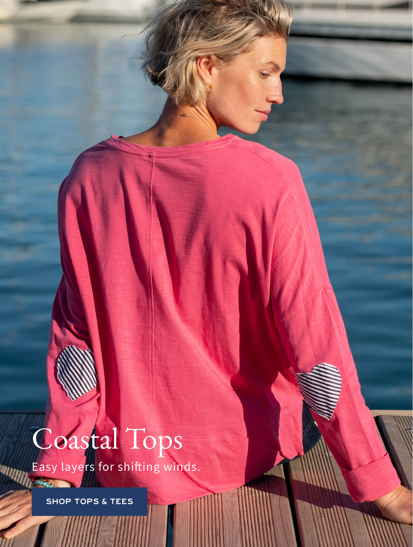 Pink knit top with striped patch details on the sleeves. Text: Coastal Tops Easy layers for shifting winds. SHOP TOPS & TEES