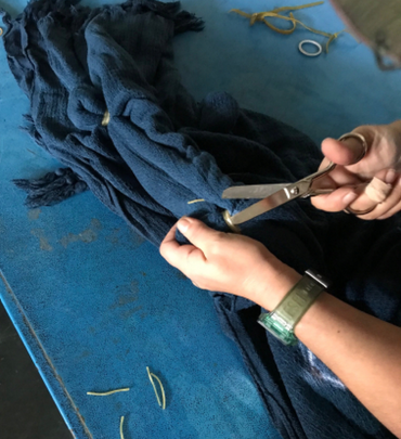hands holding scissors cutting blue fabric