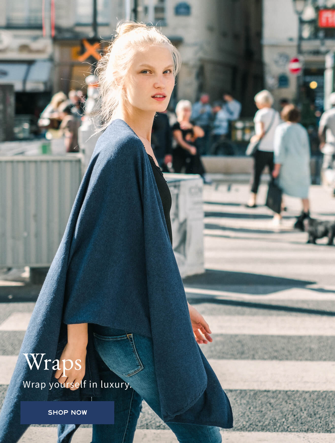 Navy blue wrap in a soft knit material with a large draped fold. Text: Wraps Wrap yourself in luxury. SHOP NOW